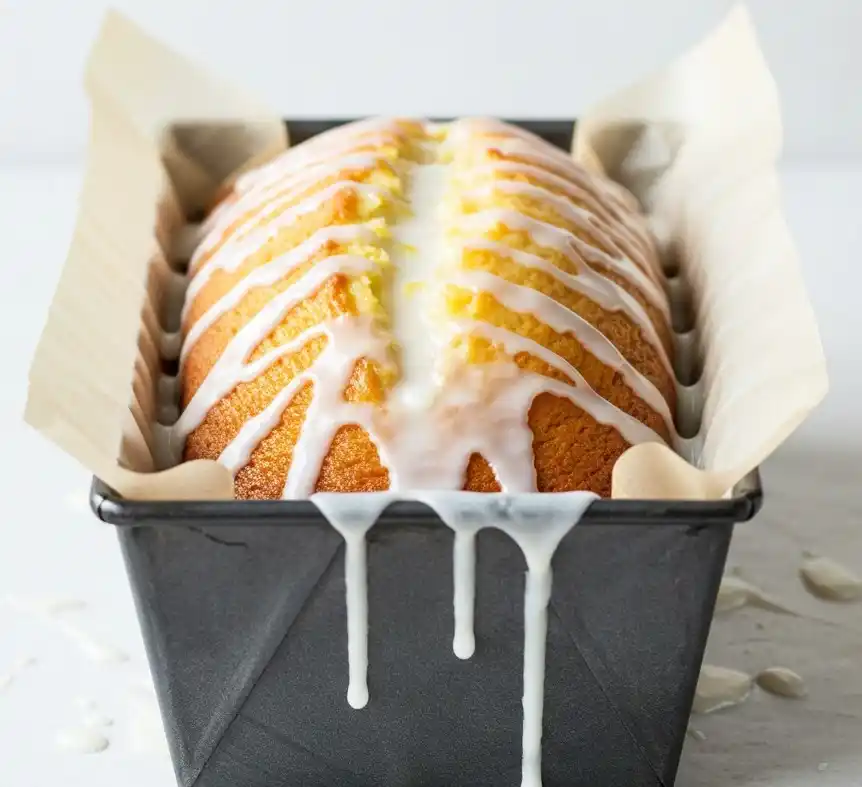 Gâteau yaourt citron présenté dans un moule, avec un glaçage au citron qui coule légèrement sur les côtés, prêt à être dégusté.