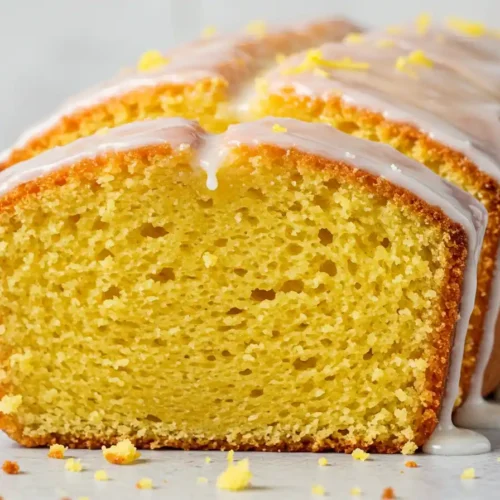 Une tranche de gâteau yaourt citron parfaitement coupée, mettant en valeur sa texture légère et aérienne, surmontée d'un glaçage citronné.