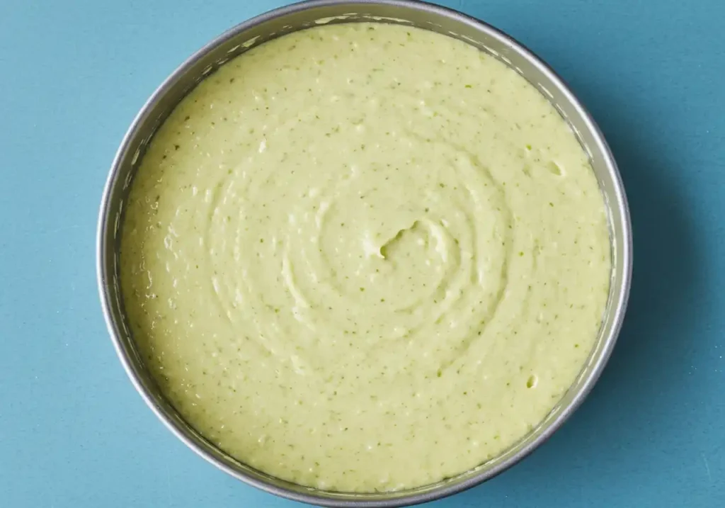 Pâte à Gâteau Pistache verte et lisse versée dans un moule rond, prête pour la cuisson.