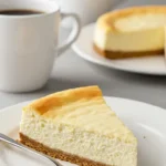 Une part de gâteau au fromage et deux tasses de café sur une table.