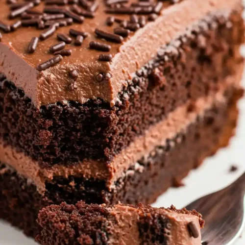 Une part de gâteau merveilleux au chocolat, avec glaçage et décorations, sur une fourchette.