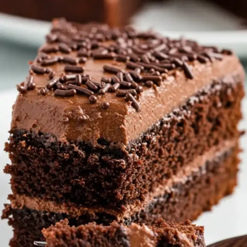 Gros plan d'une part de gâteau merveilleux au chocolat, avec glaçage crémeux, vermicelles au chocolat, et une part embrochée sur une fourchette.